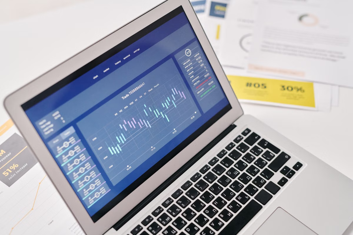 A laptop beside financial documents showing analytics